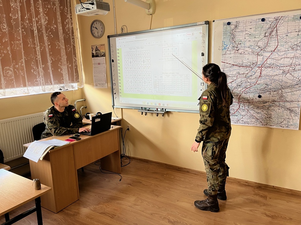 Instruktor przy mapie wyświetlanej na tablicy interaktywnej prowadzi szkolenie