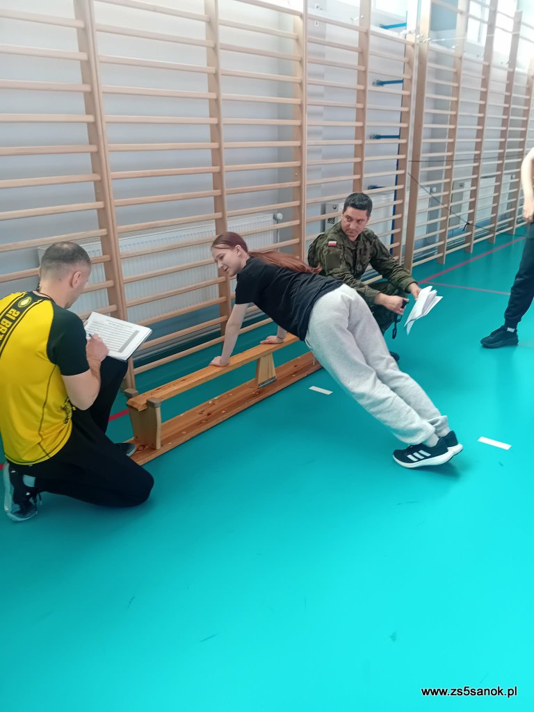 Sala gimnastyczna - uczniowie wykonują ćwiczenia pod nadzorem instruktora