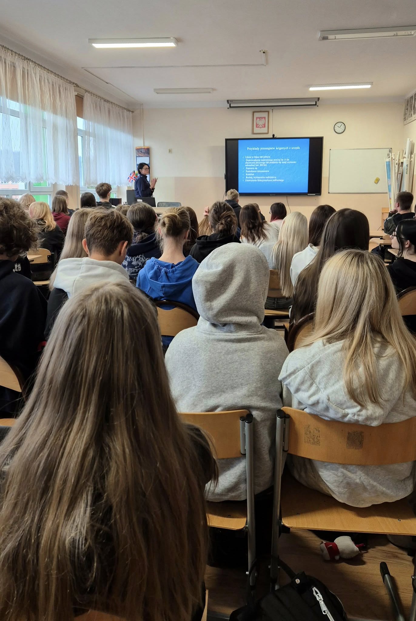 Uczestnicy wykładu na tle tablicy pokazani od tyłu.